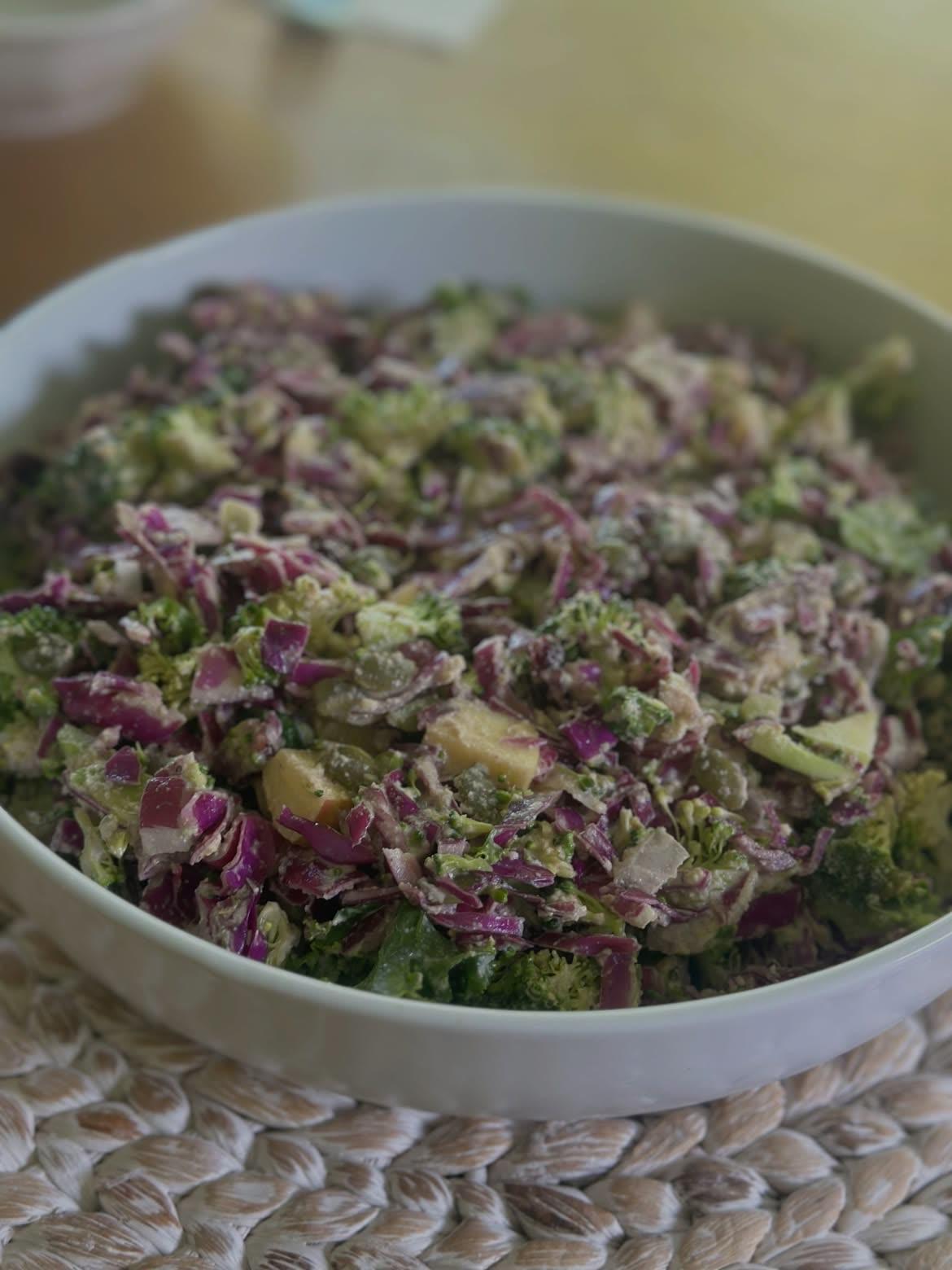 Red cabbage and broccoli slaw in a white bowl